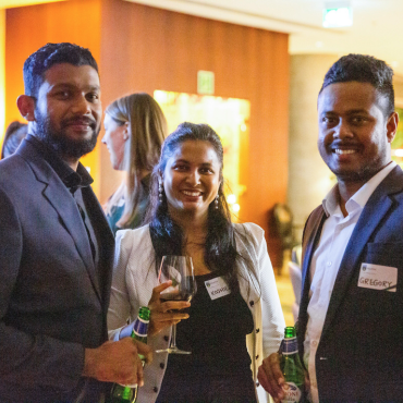 Three alumni smiling at the camera at a global event in Vancouver.